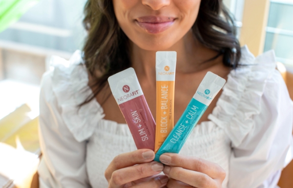 A woman holding up sachets from the NeoraFit™ Weight Management & Wellness Set.