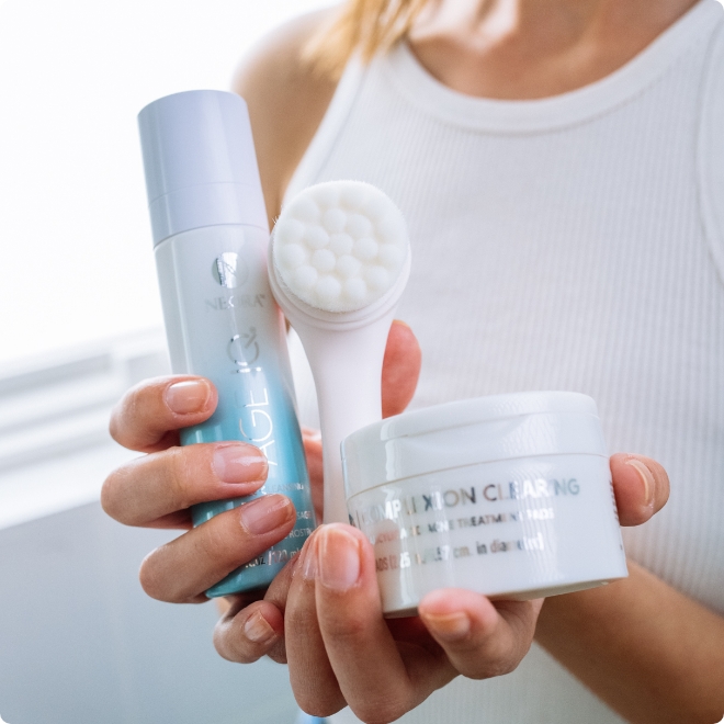 Woman holding Neora’s hottest holiday must-have, the Clear Skin Set, which includes Age IQ Double-Cleansing Face Wash, Complexion Clearing Pads and FREE FREE Dual-Action Facial Cleansing Brush. 
